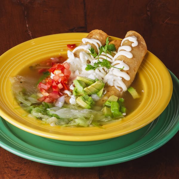 Los Alebrijes Mexican Restaurant's taquitos in broth with lettuce, avocado, tomato, and sour cream.