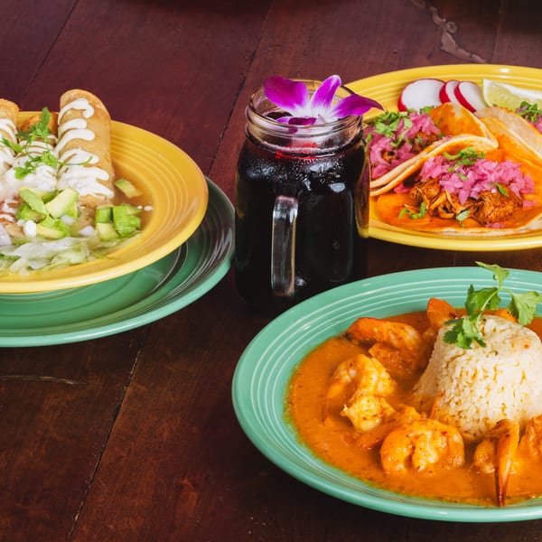 Three vibrant Mexican dishes: taquitos, tacos al pastor, and shrimp in red sauce with rice.